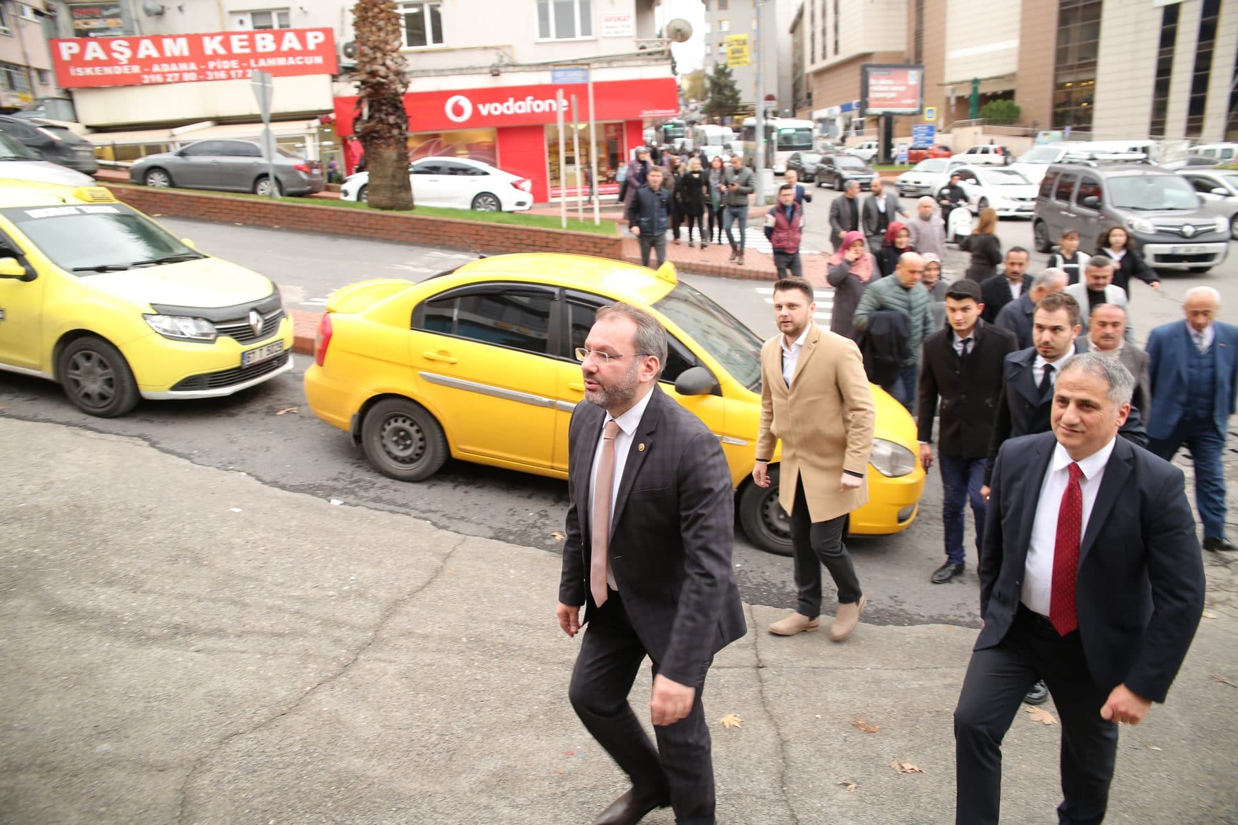 Ömer Yazıcıoğlu and his companions walking along a street lined with taxis