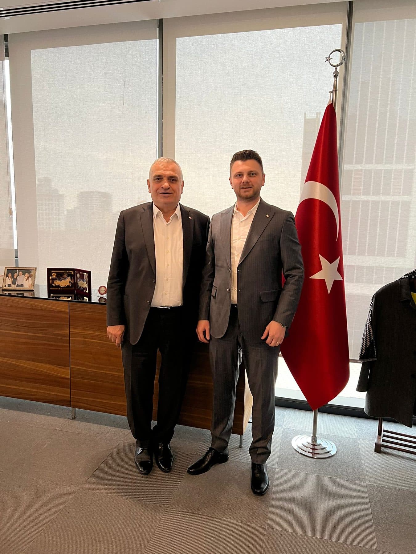 Ömer Yazıcıoğlu with an official in a high-rise office, in front of a Turkish flag