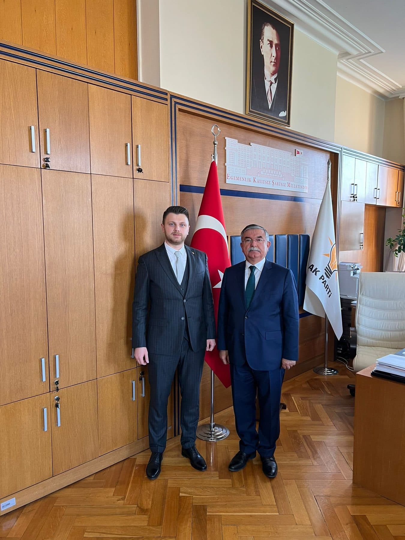Ömer Yazıcıoğlu with a district governor in an office, in front of a Turkish flag and party pennant